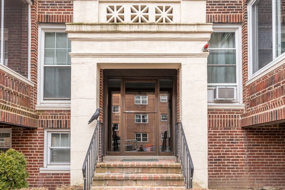 Front view of a brick building entrance with a white stone frame and steps.