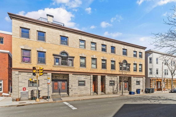 Front view of a three-story building with brick facade and multiple rectangular windows.