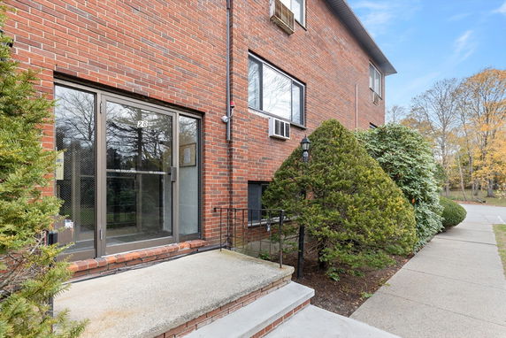 Front view of a brick multi-story building entrance with glass doors and windows.