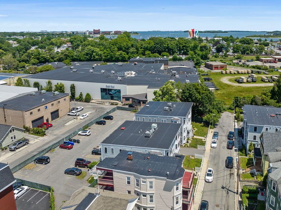 Panoramic view showing various buildings and parking areas with a water body in the background