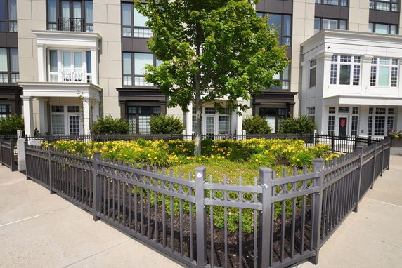 Front view of a multi-story building with a fenced garden area.