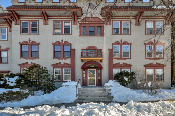 Front view of a multi-story building with decorative red trim and a central entrance.