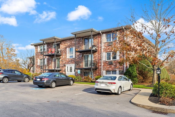 Front view of a multi-story brick apartment building with balconies.