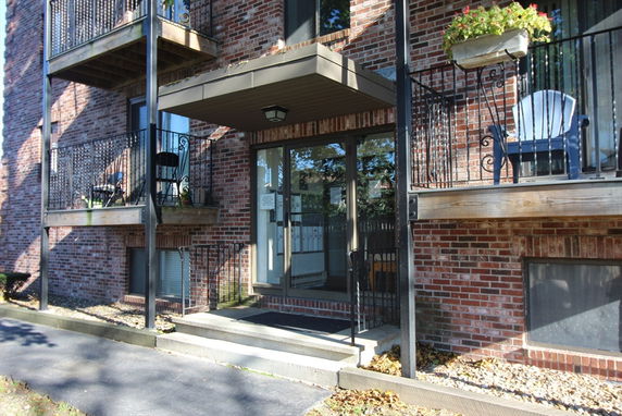 Front view of an apartment building with brick facade and balconies.