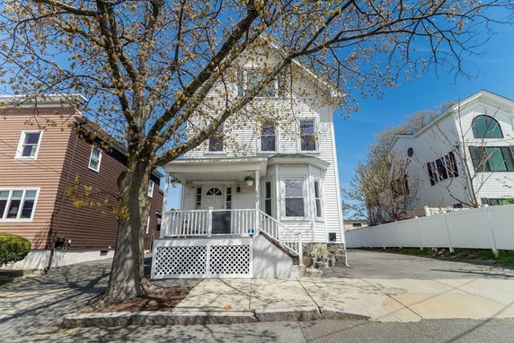 Front view of a two-story house with a porch and white siding.