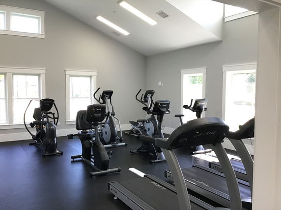 Indoor gym area with exercise equipment including treadmills and stationary bikes.