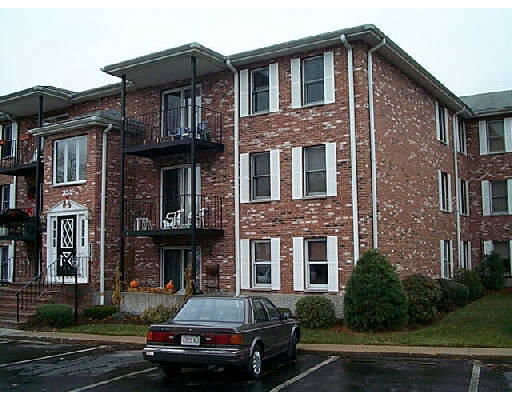 Front view of a brick apartment building with balconies and parking spaces.