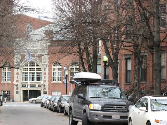 Front view of a large brick building with arched windows and decorative stonework.