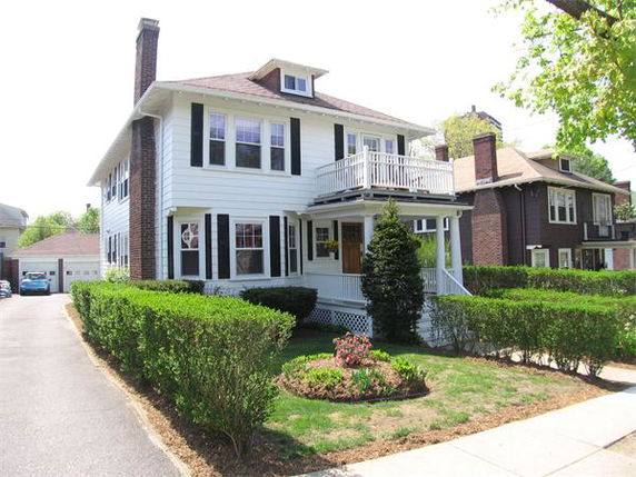 Front view of a two-story house with a balcony and chimney.