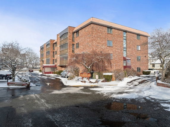 Front view of a multi-story brick building with a snowy driveway.