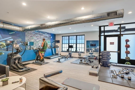 Indoor gym area with exercise equipment and a person using a stationary bike.