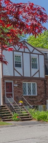 Front view of a two-story house with a brick facade and decorative timber framing.