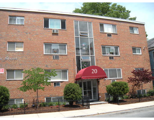 Front view of a three-story brick apartment building with a central entrance and an awning.