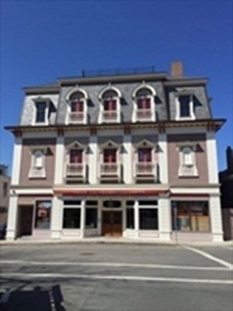 Front view of a three-story building with arched windows and a decorative facade.