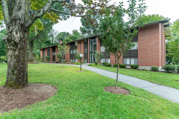 Front view of a two-story brick building with large windows and a pathway leading to the entrance.