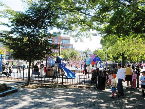 Outdoor playground with slides and people gathered around.