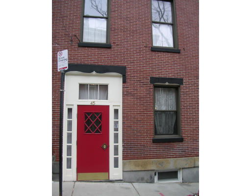 Front view of a brick building with a red door and two windows.