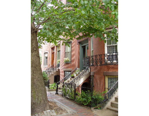 Front view of a row of brick townhouses with stairs and iron railings.