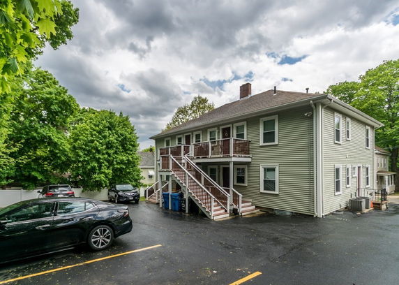 Rear view of a two-story building with a parking area and staircase.