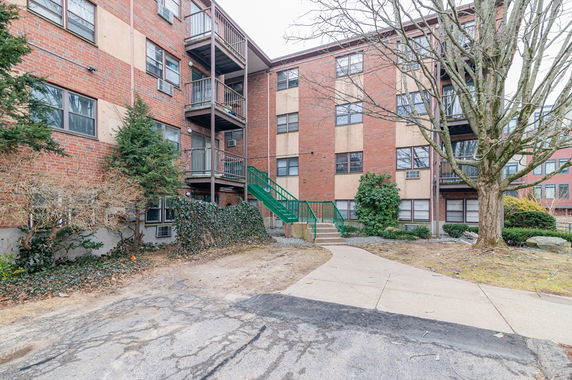 Front view of a multi-story brick apartment building with balconies.