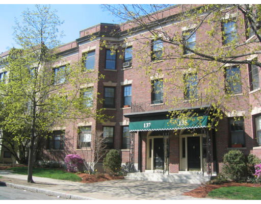 Front view of a multi-story brick apartment building with a green awning