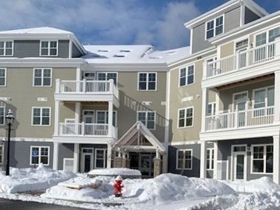 Front view of a multi-story residential building with balconies, covered in snow.