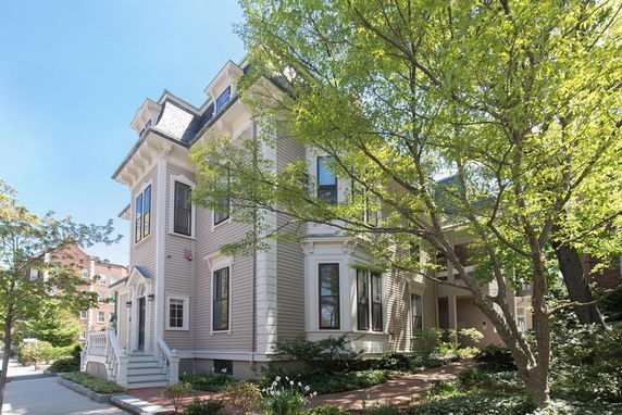 Front view of a two-story house with a mansard roof and bay windows.