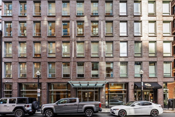 Front view of a multi-story brick building with large windows and a glass entrance canopy.