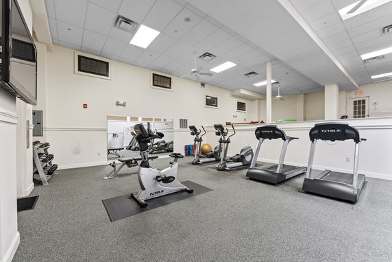 Interior view of a gym area with exercise equipment including treadmills and stationary bikes.