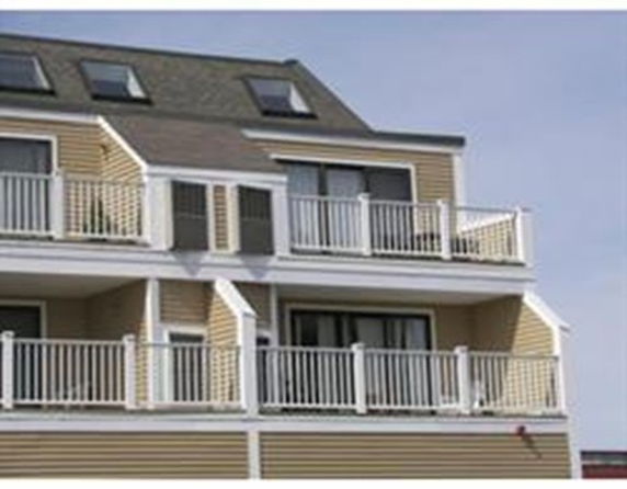Front view of a multi-story building with balconies and a sloped roof with skylights.