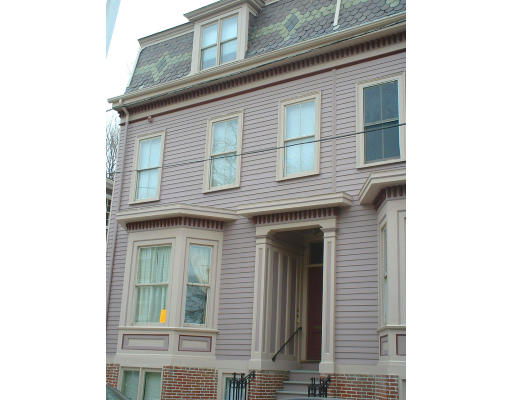 Front view of a multi-story house with decorative trim and a mansard roof.