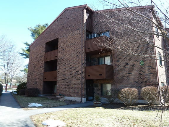 Front view of a multi-story brick apartment building with balconies.