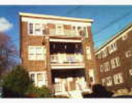 Front view of a multi-story brick apartment building with balconies.