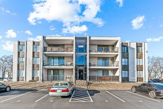 Front view of a three-story apartment building with balconies and large windows.