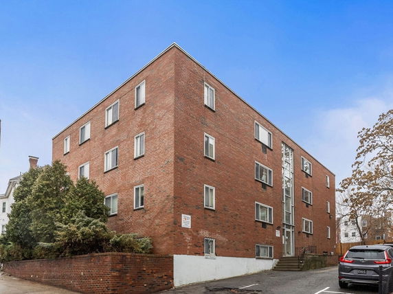 Front view of a brick apartment building with multiple windows.