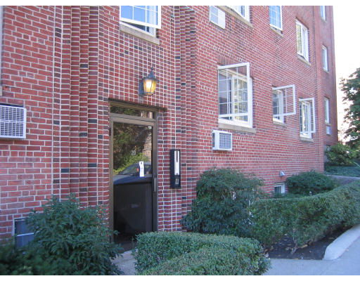 Front view of a brick apartment building entrance with multiple windows.
