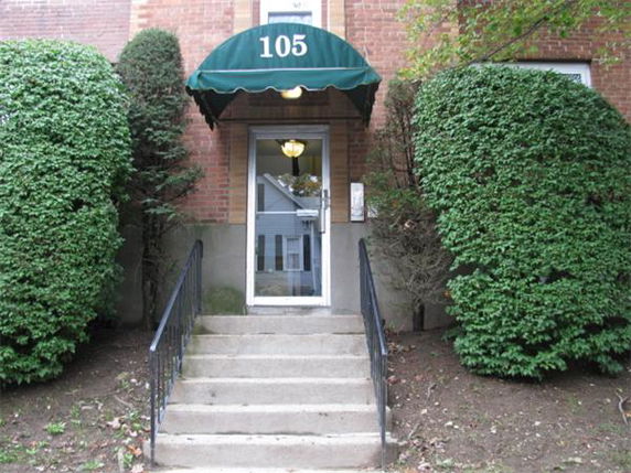 Front view of a building entrance with steps and a green awning labeled 105.