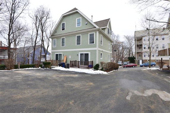 Front view of a multi-story house with a light green facade and gabled roof.