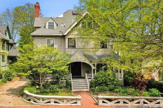 Front view of a multi-story house with a porch and dormer windows.