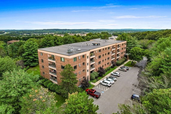 Front view of a four-story brick apartment building with balconies.