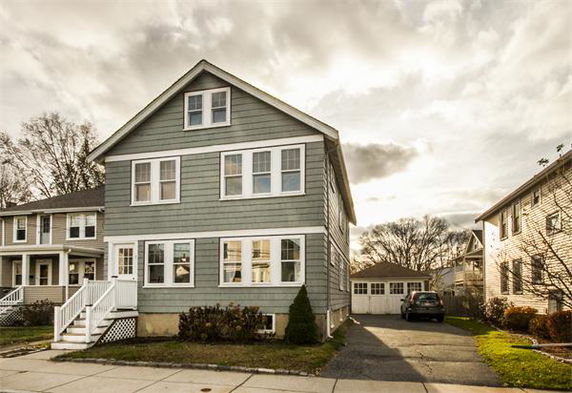 Front view of a two-story house with a sloped roof and multiple windows.