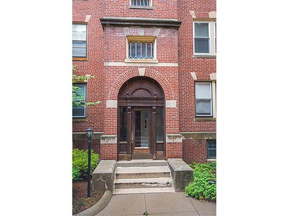 Front view of a brick apartment building with an arched entrance.