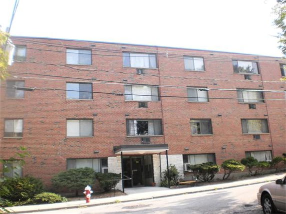 Front view of a multi-story brick apartment building with multiple windows.