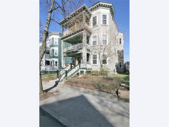 Front view of a multi-story house with an elevated entrance and porches.