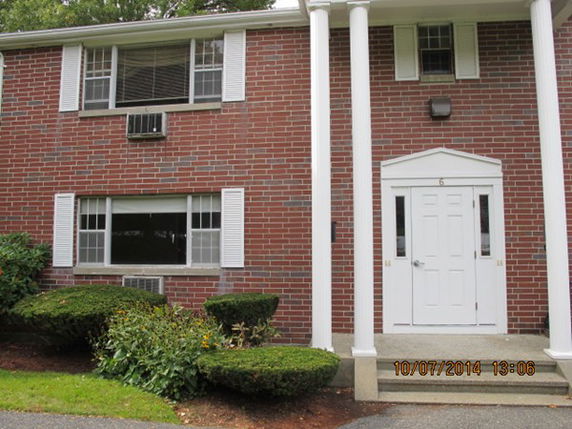 Front view of a two-story brick building with white columns and a white door.