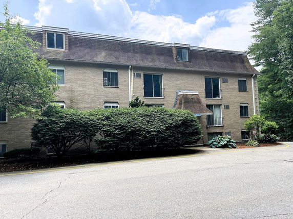 Front view of a multi-story residential building with a distinctive roof design.