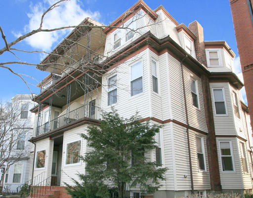 Front view of a multi-story residential building with bay windows and a balcony.
