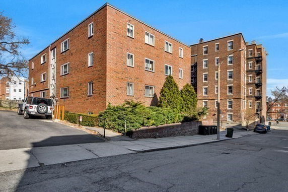 Front view of a multi-story brick apartment building with multiple windows.