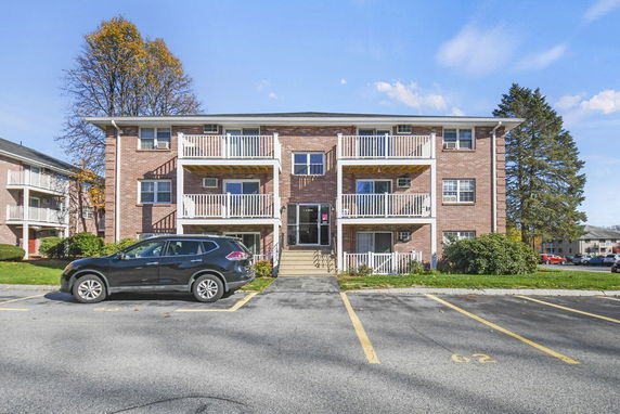 Front view of a three-story brick apartment building with balconies and a central entrance.