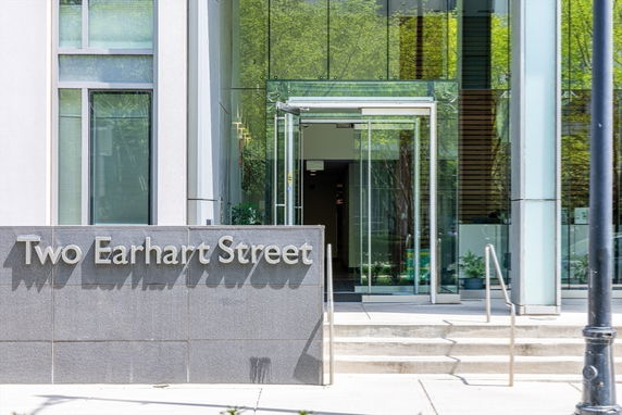 Front view of a modern building entrance with glass doors and signage reading 'Two Earhart Street.'
